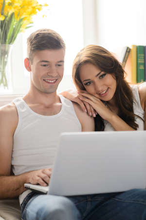 Surfing web together. Beautiful young couple sitting close to each other and reading booksの写真素材
