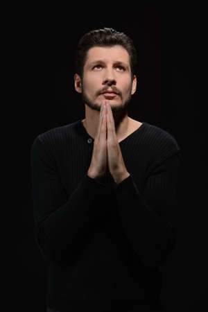 Praying to god. Portrait of bearded man praying and holding his hands claspedの写真素材