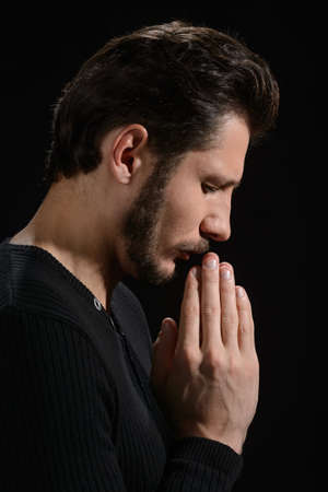 The power of prayer. Side view of bearded man praying and holding his hands claspedの写真素材