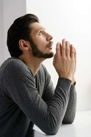 Bearded man praying. Portrait of bearded man praying to god and holding his hands claspedの写真素材