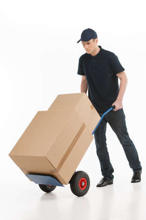 Moving house. Full length of young deliveryman with a hand truck transporting the cardboard boxesの写真素材
