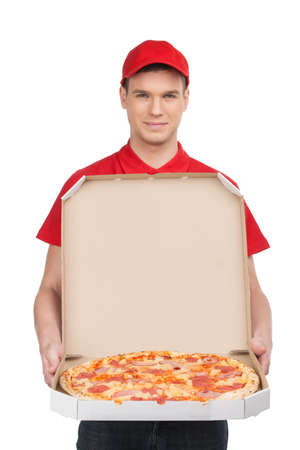 Pizza delivery. Cheerful young deliveryman holding a pizza box while isolated on whiteの写真素材