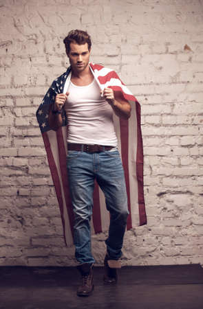 Sexy man using American flag like a cloak. Walking forward, showing his outfitの写真素材