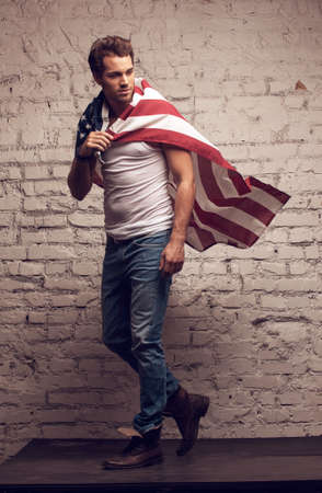 Handsome man walking using American flag like a cloak. Looking awayの写真素材