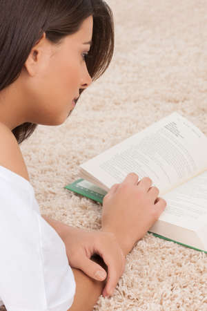 Women reading a book. Top view of young women lying down on the floor and reading a bookの写真素材