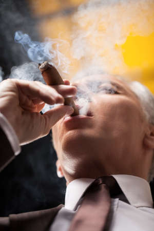 Smoking a good cigar. Low angle view of senior businessman smoking cigarの写真素材