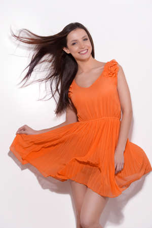 Beauty in orange dress. Beautiful young woman in orange dress posing and smiling isolated on whiteの写真素材