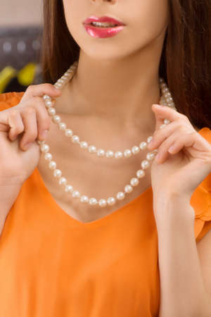 Pearl necklace. Cropped image of beautiful young woman putting on pearl necklaceの写真素材