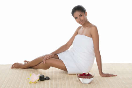 Beautiful SPA women. Beautiful young women wrapped in towel sitting near SPA equipment and smiling at cameraの写真素材