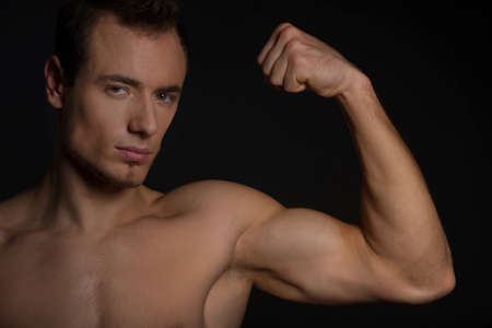 Handsome man showing his muscles. Isolated on black