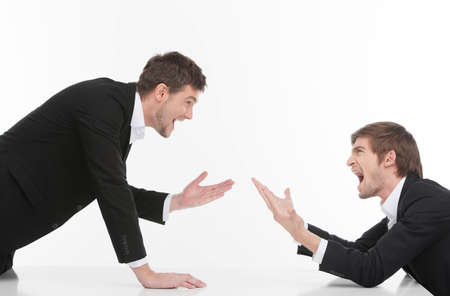 Men confrontation. Two angry young business people shouting and gesturing while isolated on whiteの写真素材