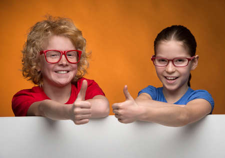 Kids gesturing. Cheerful children in glasses looking at camera and gesturing while standing isolated...