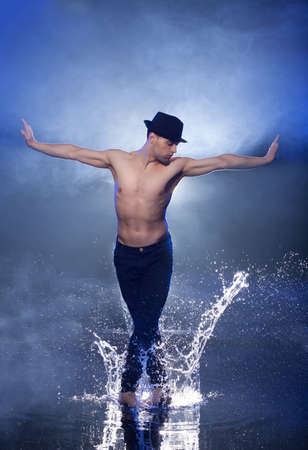 Wet dancer. Young male dancer in black fedora dancing on the wet floorの写真素材