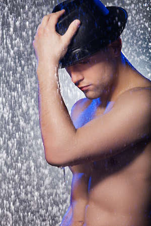Wet handsome. Handsome young men in black fedora standing under the rainの写真素材