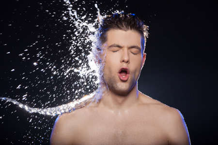 Water on face  Portrait of young wet men and the water splashing on his faceの写真素材