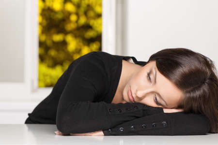 Depressed woman. Young sad woman sitting at the table and looking away
