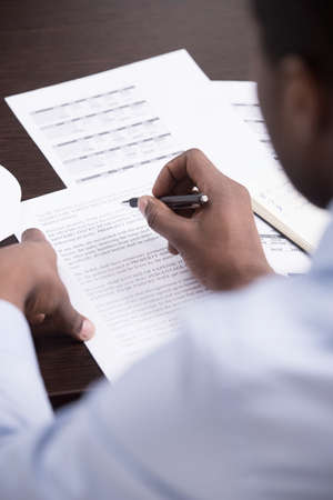 Checking the documents. Top view of African descent men writing something on the papers