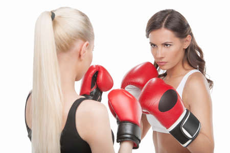 Women boxing. Two confident women boxing while standing isolated on white