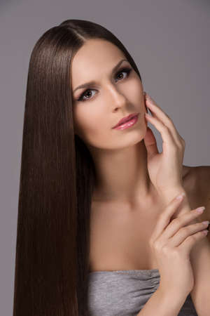 Beautiful women. Portrait of beautiful young women with her hand on chin looking at camera while isolated on greyの写真素材