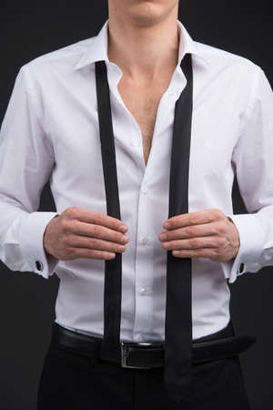 Close up of man starting tying a tie. Wearing classical suite.の写真素材