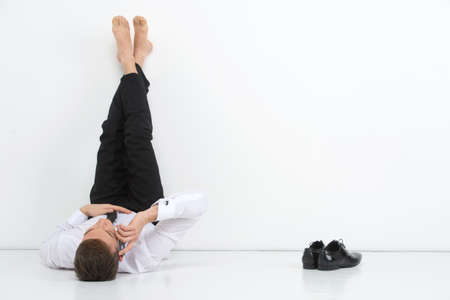 Man talking by phone. While giving a ret to his bare feetの写真素材