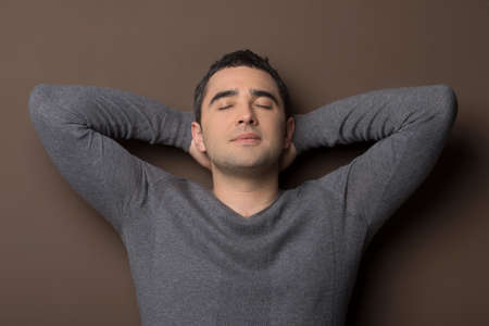 Man relaxing. Relaxed middle-aged man leaning on the wall and holding his head in handsの写真素材