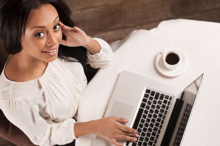 Beauty with laptop.  Top view of beautiful African descent women working on laptop and looking at cameraの写真素材