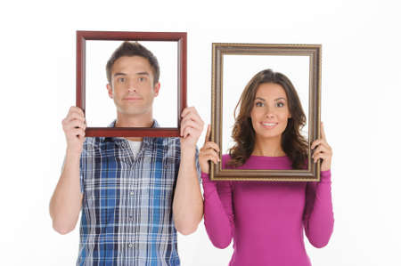 Couple with picture frames. Beautiful young couple looking through a picture frames and smiling while isolated on whiteの写真素材