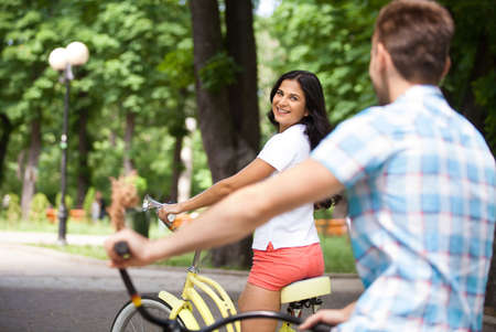Bike ride. Cheerful young couple riding bikes in parkの写真素材