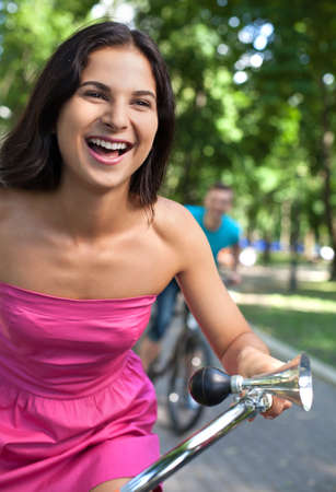 Bike ride at park. Cheerful young couple riding bikes in parkの写真素材