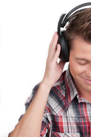 Man in headphones. Cropped image of handsome young man in headphones keeping his eyes closed while isolated on whiteの写真素材