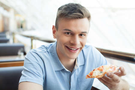Man eating pizza. Cheerful young man eating pizza at the restaurant
