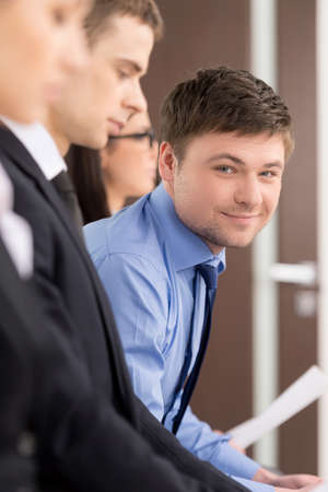 Handsome businessman is looking an smiling. Blur foreground. Sitting in the officeの写真素材