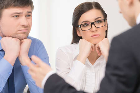 Two people listening to man. Woman with attention and man with bored face.の写真素材