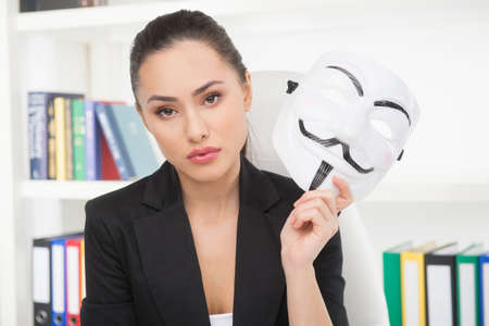 Businesswoman with mask. Confident young woman holding mask in her hand and looking at cameraの写真素材