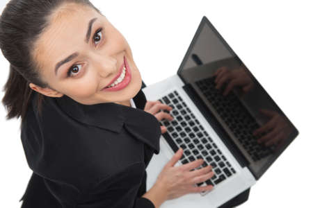 Businesswoman with laptop. Top view of beautiful young woman working at the laptop while isolated on whiteの写真素材