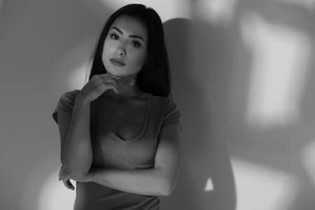 Thoughtful beauty. Black and white image of beautiful young woman holding hand on chin and looking at cameraの写真素材