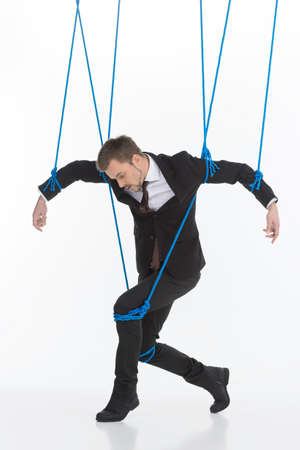 Business marionette  Young man in formalwear looking like marionette moving against white backgroundの写真素材