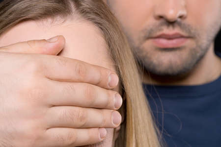 Close up of man and woman. Man closing female yes with his handの写真素材