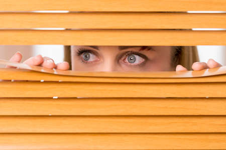Close up of female eyes looking outside from blinds. Bruise on woman faceの写真素材
