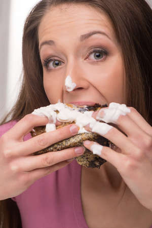 Woman eating cake. Young woman eating cake and looking at cameraの写真素材