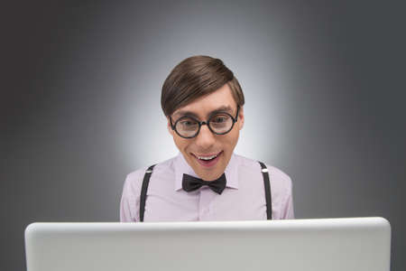 Nerd at the computer. Young nerd man working at the computer while isolated on greyの写真素材