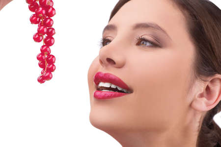 Beauty with berry. Beautiful young women holding berries in front of her face and smiling while standing isolated on whiteの写真素材