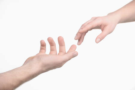 Reaching a hand. Close-up of human hands trying to reach each otherの写真素材