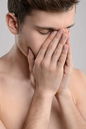 Tired men. Portrait of young shirtless men covering his face with hand and keeping eyes closed while...
