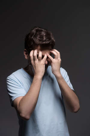 Disappointed men. Portrait of sad men covering his face with hands while isolated on greyの写真素材