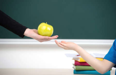 Sharing is good. Close-up of teacher giving an apple to the kidの写真素材