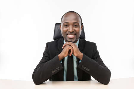 Businessman sitting with hands clasped and smileの写真素材