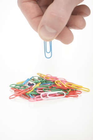 Hand holding paper clip across others clipsの写真素材