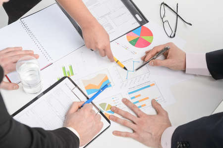 Human hands holding pens and papers, making notes in documents,  on the table